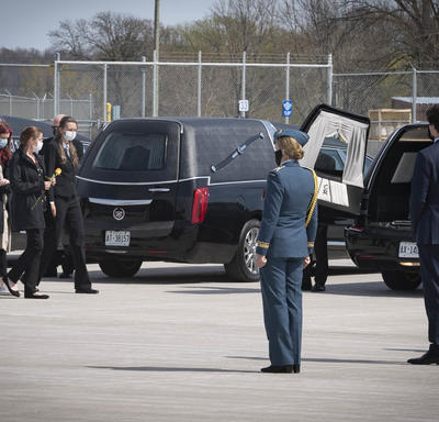 Family members of the deceased walk towards the hearse. The Governor General and the Prime Minister are standing near the hearse.