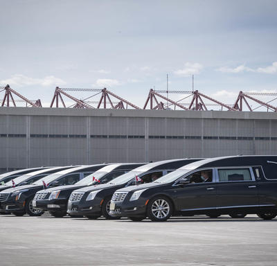 Six hearses are parked beside each other.