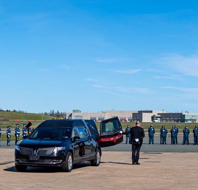 Des membres des Forces armées canadiennes, dont le général Vance, chef d'état-major de la défense, saluent le cercueil à sa sortie de l'avion. 