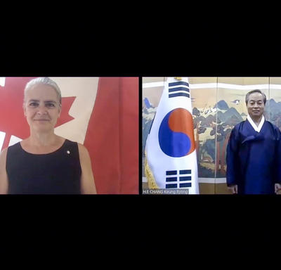 A computer screen split in two shows a woman, on the left, standing and smiling in front of a Canadian flag. On the right, a man is standing next to the flag of Korea.