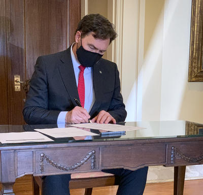 L’administrateur, assis à une table, signe un document.