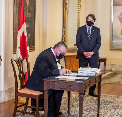 L’administrateur et le secrétaire observent un homme qui signe un document.