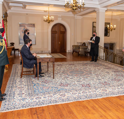 Four people standing far apart while the Administrator sits at a table.