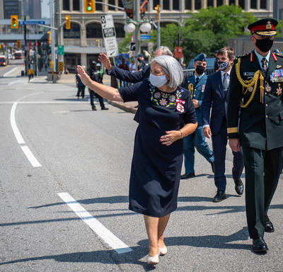 La gouverneure générale Mary May Simon salue la foule alors qu’elle se rend en marchant du Sénat au Monument commémoratif de guerre du Canada.