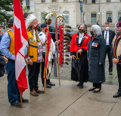 La gouverneure générale échange avec d’autres personnes rassemblées devant le monument.