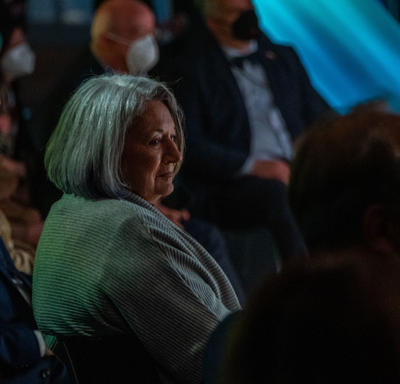 The Governor General is seated at the Canada Pavilion. The lighting is dark. She is smiling.