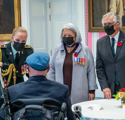 Governor General Mary Simon is talking to a Canadian veteran. He is in uniform and the Governor General is wearing military decorations and a poppy.