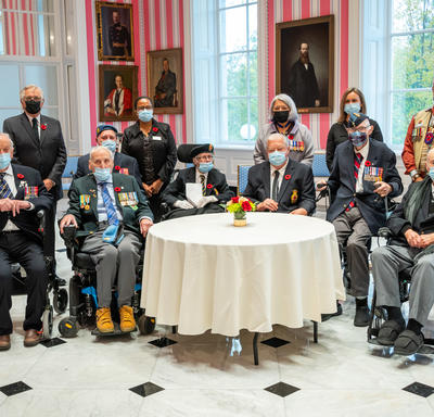  Leurs Excellences sont photographiées avec des anciens combattants canadiens. Tous les anciens combattants sont en uniforme. Ils sont dans la salle de la tente.