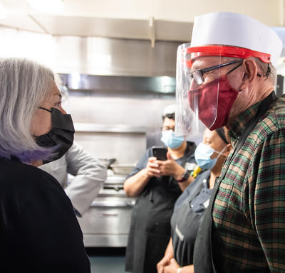 The Governor General is talking with a staff member of the Ottawa Mission. They are wearing masks. 