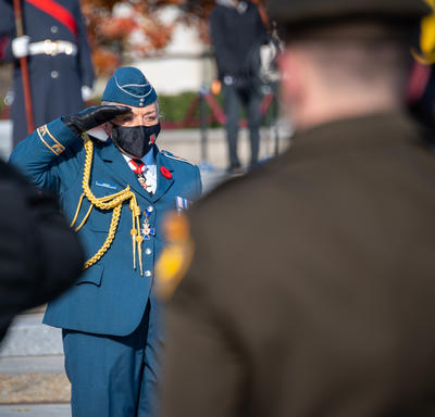 The Governor General salutes a group of military members. She is wearing the Royal Canadian Air Force uniform and a black mask.