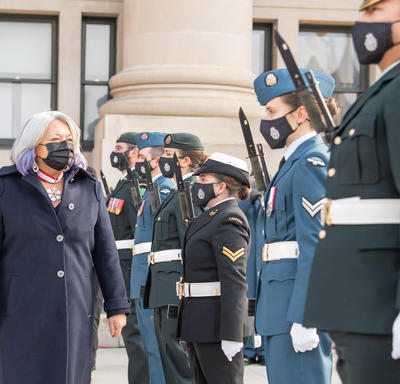 La gouverneure générale passe devant une rangée d'officiers en uniforme alors qu'elle entre au Sénat.