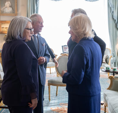 Her Excellency Mary Simon and Her Royal Highness the Duchess of Cornwall are talking to each other in the foreground. His Royal Highness The Prince of Wales and His Excellency Whit Fraser are speaking to each other behind them.