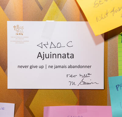 Written on a white paper are the words ‘Ajuinnata. Never give up / ne jamais abandonner’. There is also the signature of Governor General Mary Simon as well as the Inuktitut translation. 