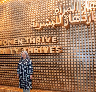 La gouverneure générale Mary Simon se tient devant un mur sur lequel sont inscrits les mots suivants :  When women thrive Humanity thrives (Quand les femmes s'épanouissent L'humanité s'épanouit).