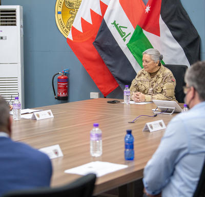 La gouverneure générale est assise à une grande table au Camp du Canada.