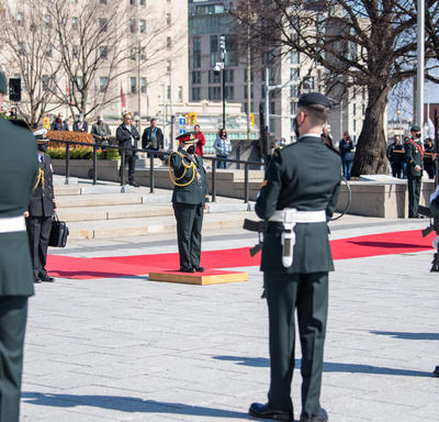 Governor General Simon is saluting. She is standing on a small podium in front of the National War Memorial.