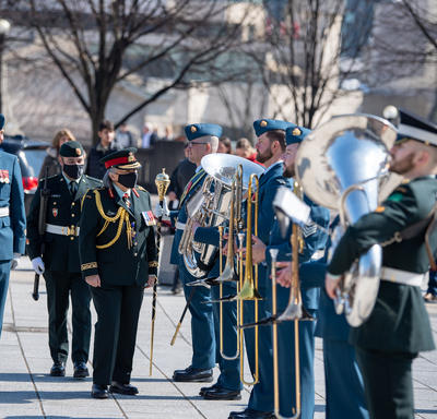 La gouverneure générale Simon marche devant une garde d’honneur au Monument commémoratif de guerre du Canada. Un homme portant un uniforme militaire marche à ses côtés.