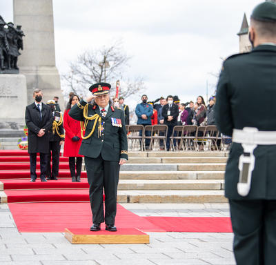 La gouverneure générale Simon salue. Elle est debout sur un petit podium devant le Monument commémoratif de guerre du Canada.