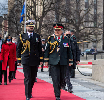 La gouverneure générale Simon marche aux côtés d'un homme en uniforme militaire.