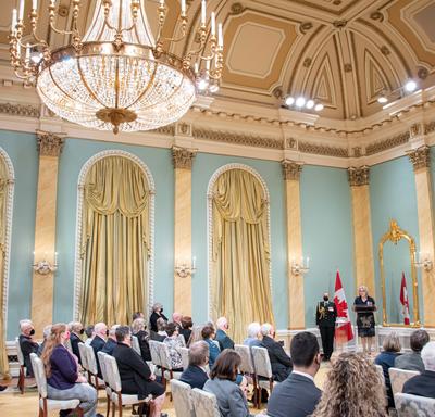 Wide angle view of the Rideau Hall ballroom, including the audience and the Governor General.
