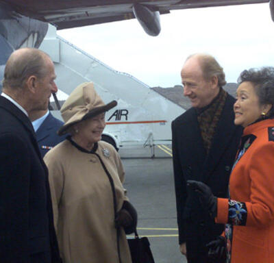 The Queen and The Duke of Edinburgh speak with Governor General Adrienne Clarkson and John Ralston Saul. They are standing on the tarmac of an airport, beside a plane. 