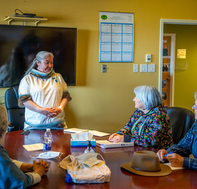 La gouverneure générale est assise à une grande table de conférence. La mairesse de Kuujjuaq est debout.  