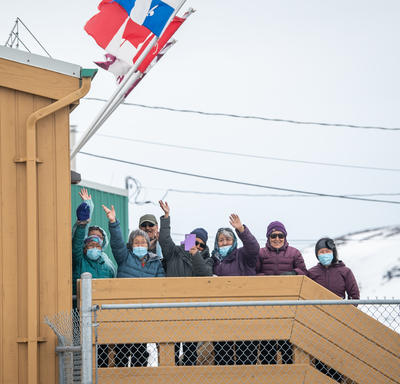 Une foule de personnes salue à l'extérieur de l'aéroport.