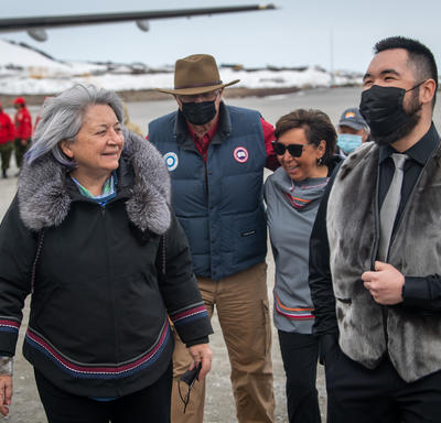 The Governor General is walking next to the Mayor of Kangiqsualujjuaq outside the airport.