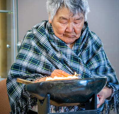 Une femme a un bol de feu devant elle.