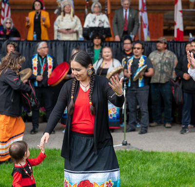 A woman is holding a little girl’s hand during a performance.