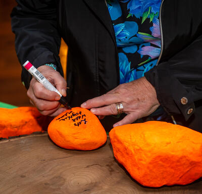 La gouverneure générale Simon écrit un message sur une pierre orange. Il est écrit : « Avançons ensemble » en anglais. Il y a une phrase en inuktitut sous la phrase en anglais.