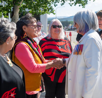 The Governor General is shaking hands with a woman. 