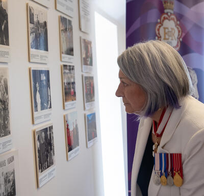The Governor General is looking at a wall of photos.