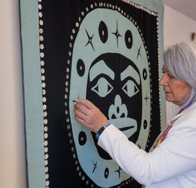 La gouverneure générale Simon admire une œuvre d’art autochtone accrochée au mur.