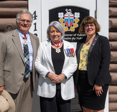A group photo. Governor General Simon is standing in the middle. Mr. Whit Fraser stands to her right. Commissioner Angélique Bernard stands to her left. They stand in front of Taylor House.
