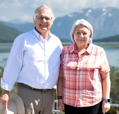 Their Excellencies smiling for the camera. A lake and mountains are behind them.