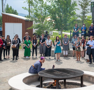 Les gens sont debout et forment un cercle autour d'un grand feu de camp.