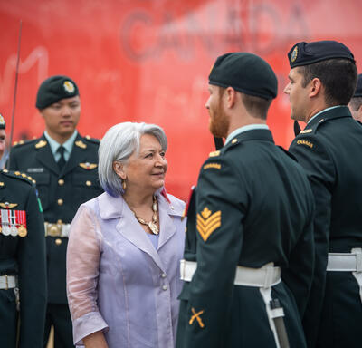 The Governor General is speaking with members of the guard of honour wearing the Canadian Armed Forces Uniform.