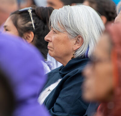 La gouverneure générale Mary Simon est assise au milieu d'une foule. Elle regarde droit devant elle.