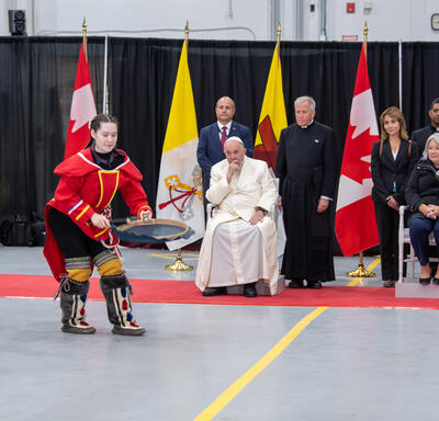 Des musiciens vêtus de vêtements traditionnels inuits se produisent. La gouverneure générale Simon, le pape François et plusieurs autres personnes regardent.