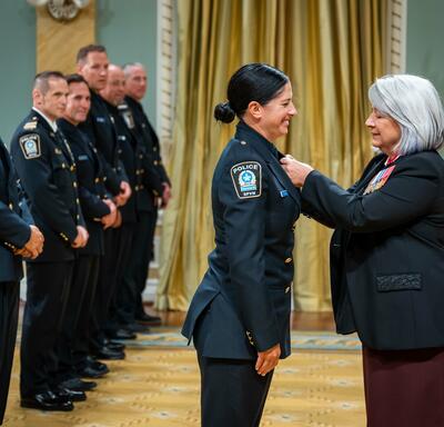 The Governor General is placing a medal on Bravery recipient Constable Annie Arseneau.