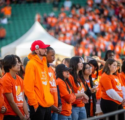 Une foule de personnes portant des chandails orange dans un stade.