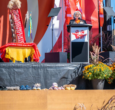 La gouverneure générale Mary Simon est debout sur une scène, derrière un pupitre. Elle parle dans un microphone.
