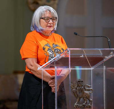 Governor General Simon is speaking into a microphone.