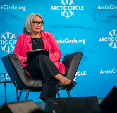 Governor General Simon is seated in a black armchair on stage. The screen behind her reads Arctic Circle. 