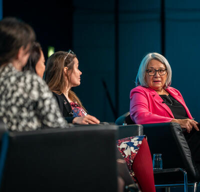 Governor General Simon and three other people are seated in black armchairs. Governor General Simon is speaking and three other panelists are looking at her.