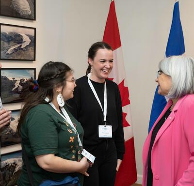 The Governor General is speaking to two people in a room. A Canada flag and an Iceland flag are in the background.