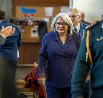 The Governor General is walking past a row of people. His Excellency is behind her.