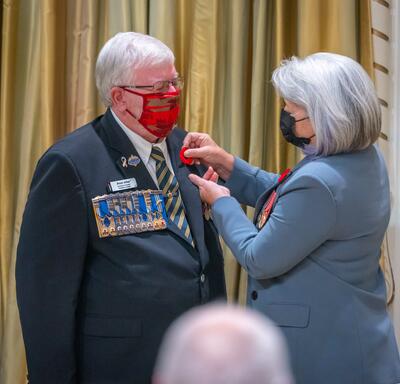 The Governor General pins a poppy onto a man’s lapel.