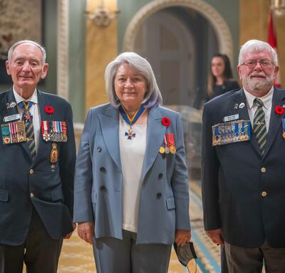 La gouverneure générale pose avec deux hommes de la Légion royale canadienne.